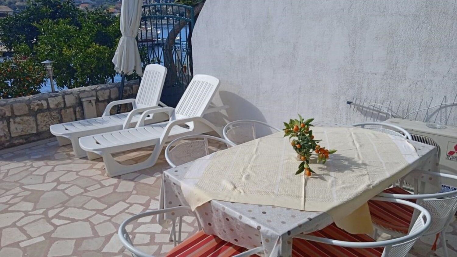 Una terrazza con tavolo e sedie, una pianta in vaso e vista sul mare.