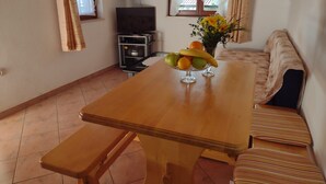 Un accogliente soggiorno con un tavolo da pranzo in legno, una panca, un divano e una TV.