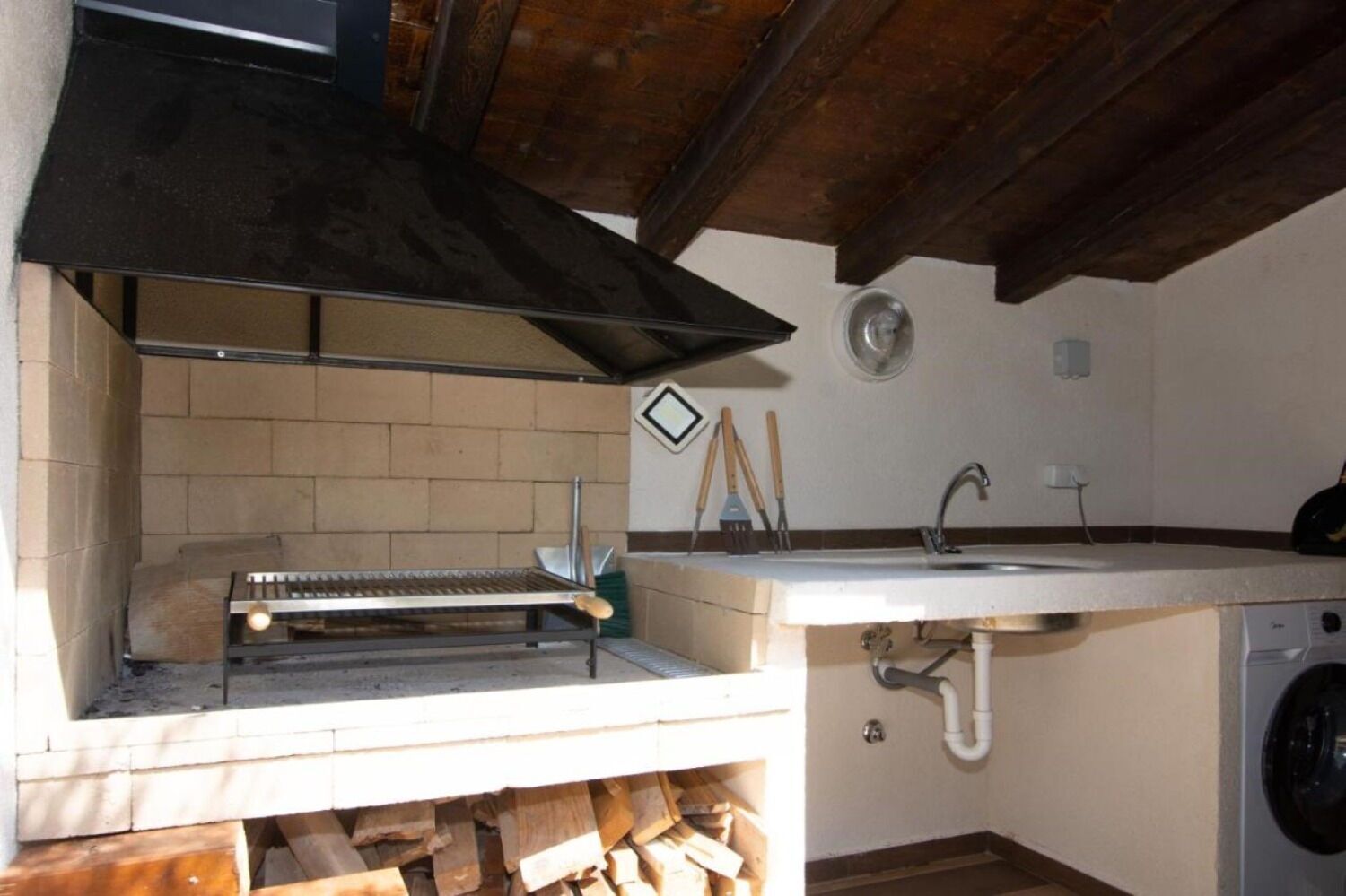 Une cuisine compacte équipée d’un barbecue intégré, d’un évier et d’un lave-linge.