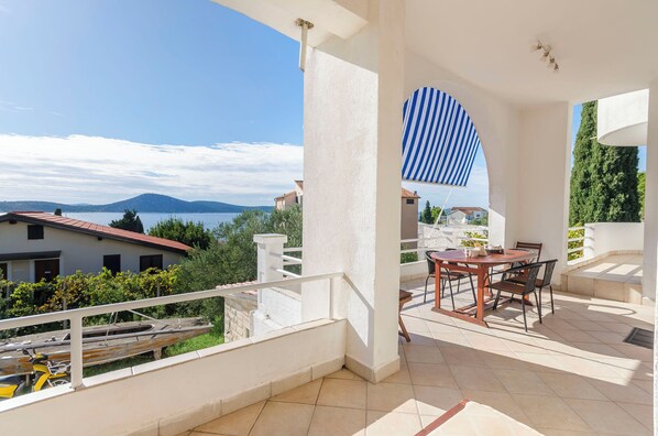 En balkon med et bord og stole, der ud til et vandområde og fjerne bjerge.