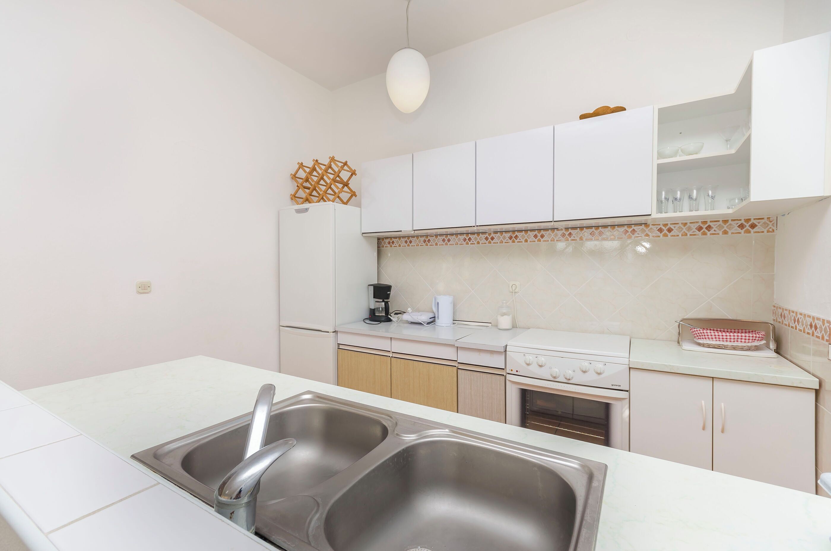 A kitchen with white cabinets, a double sink, a coffee maker, and a microwave.