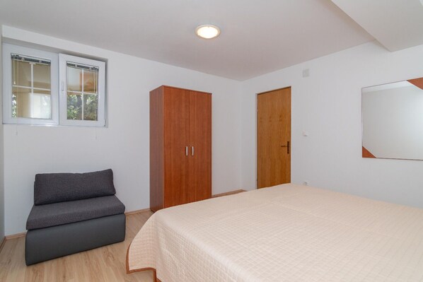Une chambre à coucher avec un lit, une armoire, un banc et une fenêtre.