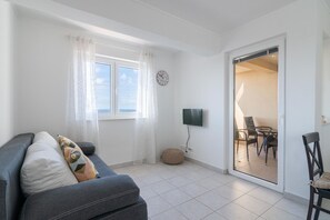 Una sala de estar moderna con un sofá gris, un televisor de pantalla plana y un comedor con sillas y una mesa.
