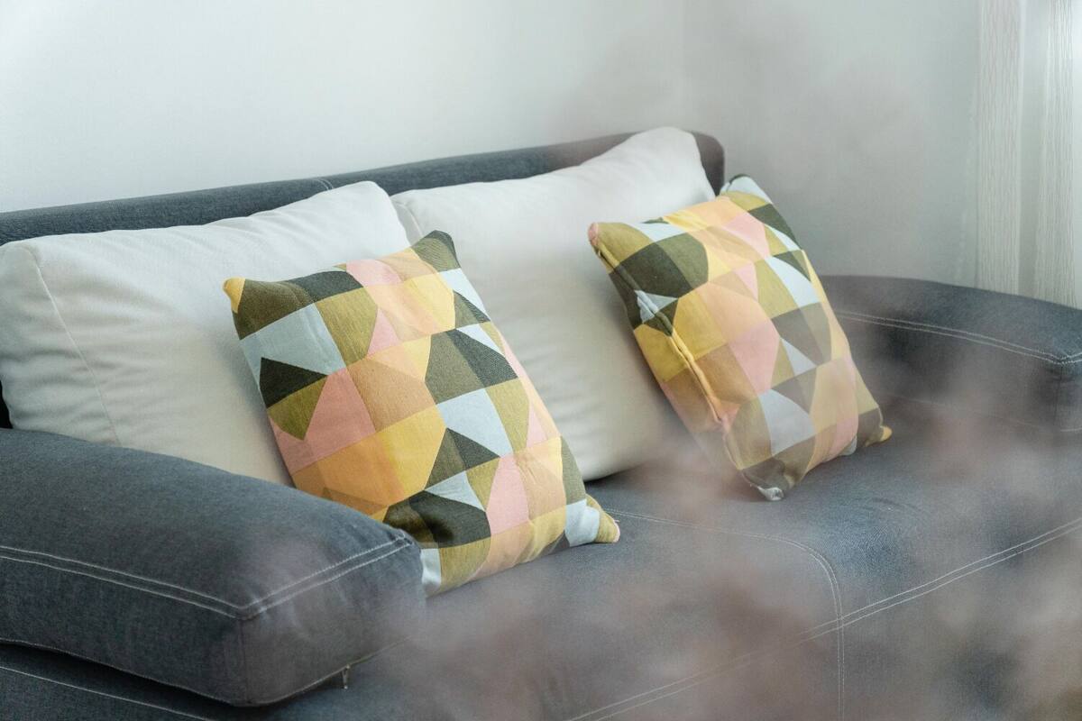A grey sofa with two patterned cushions and a plain white cushion.