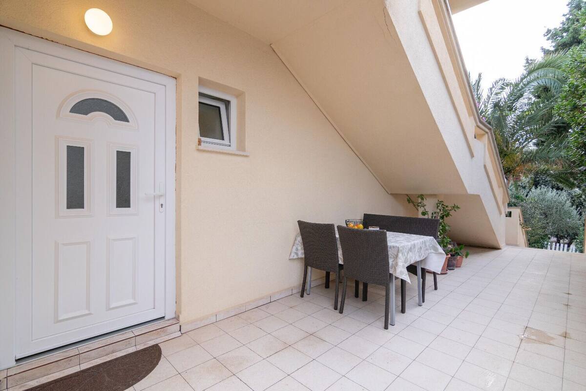 A covered outdoor dining area with a table and chairs, a door, and a small window.