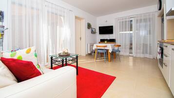 A modern living room with a sofa, a dining table, and a kitchen area.