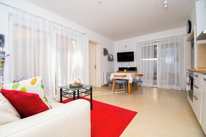 A modern living room with a sofa, a dining table, and a kitchen area. - Apartments Apartmani Oh La La (Supetar)