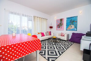 A modern living room with a red polka dot table, a white sofa, and a black and white patterned rug. - Apartments Apartmani Oh La La (Supetar)