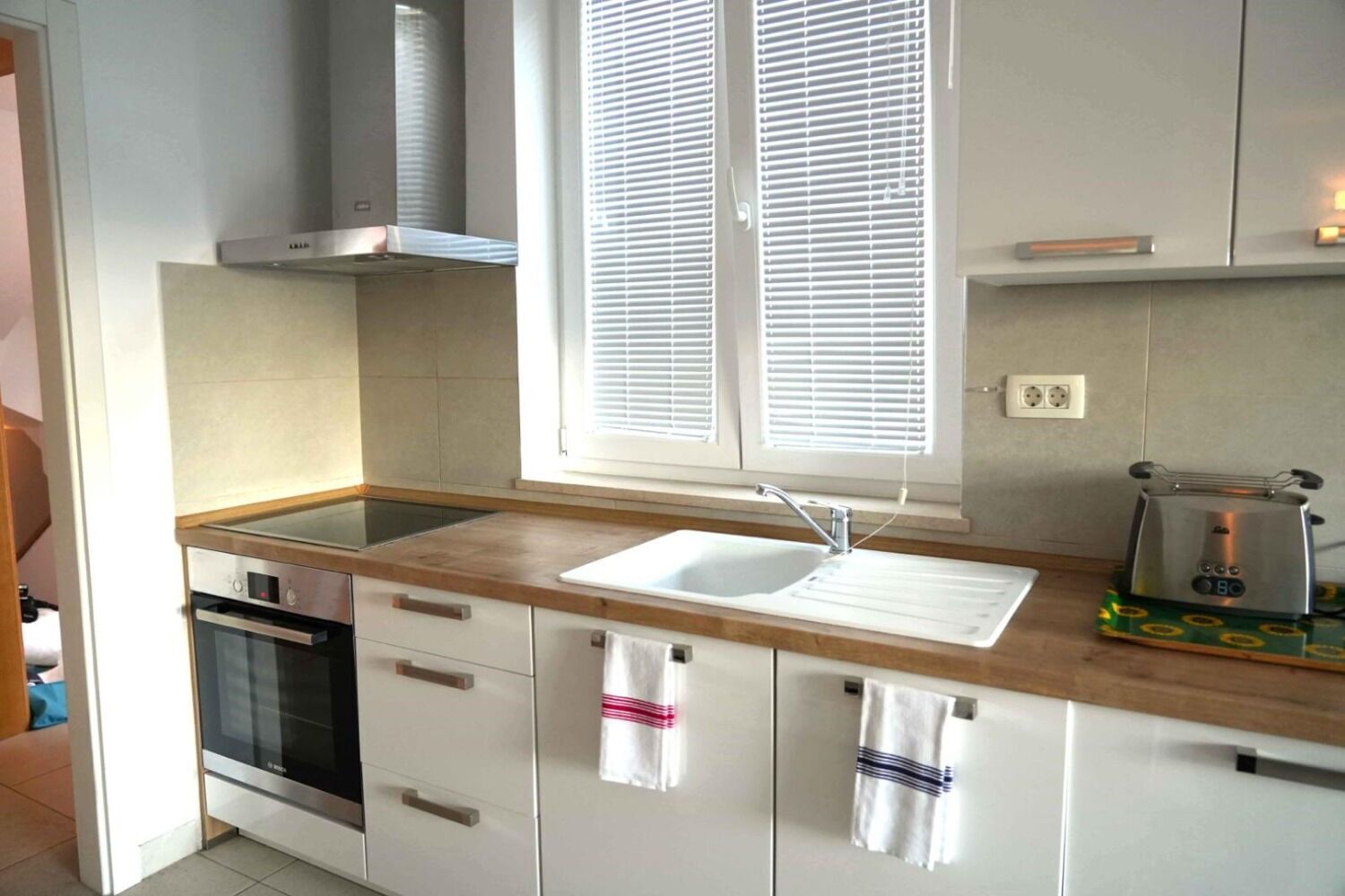 A modern kitchen with a built-in oven, a sink, and a toaster.