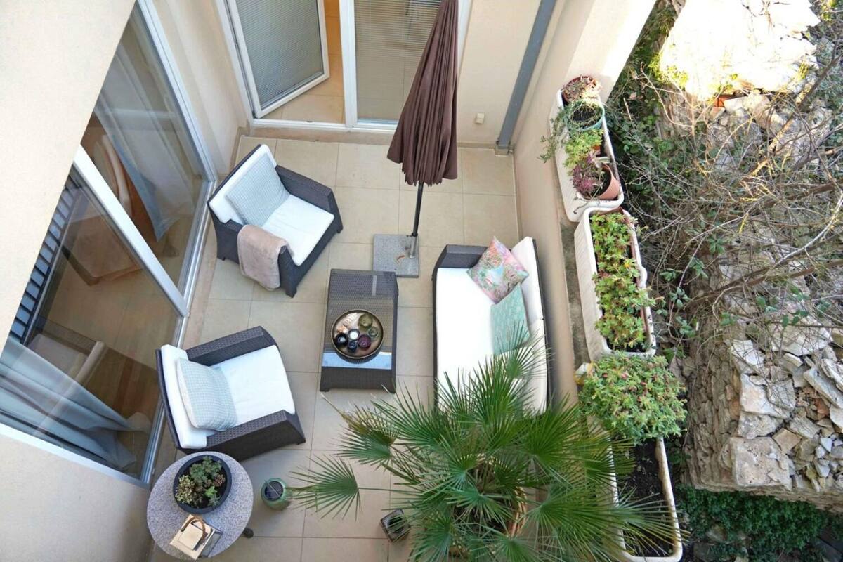A rooftop terrace with two lounge chairs, a small table with a decorative bowl, and a potted plant.