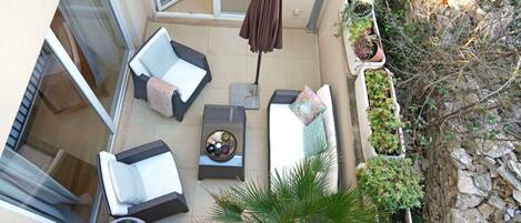 Une terrasse sur le toit, avec deux chaises longues, une petite table surmontée d’un bol décoratif et une plante en pot.