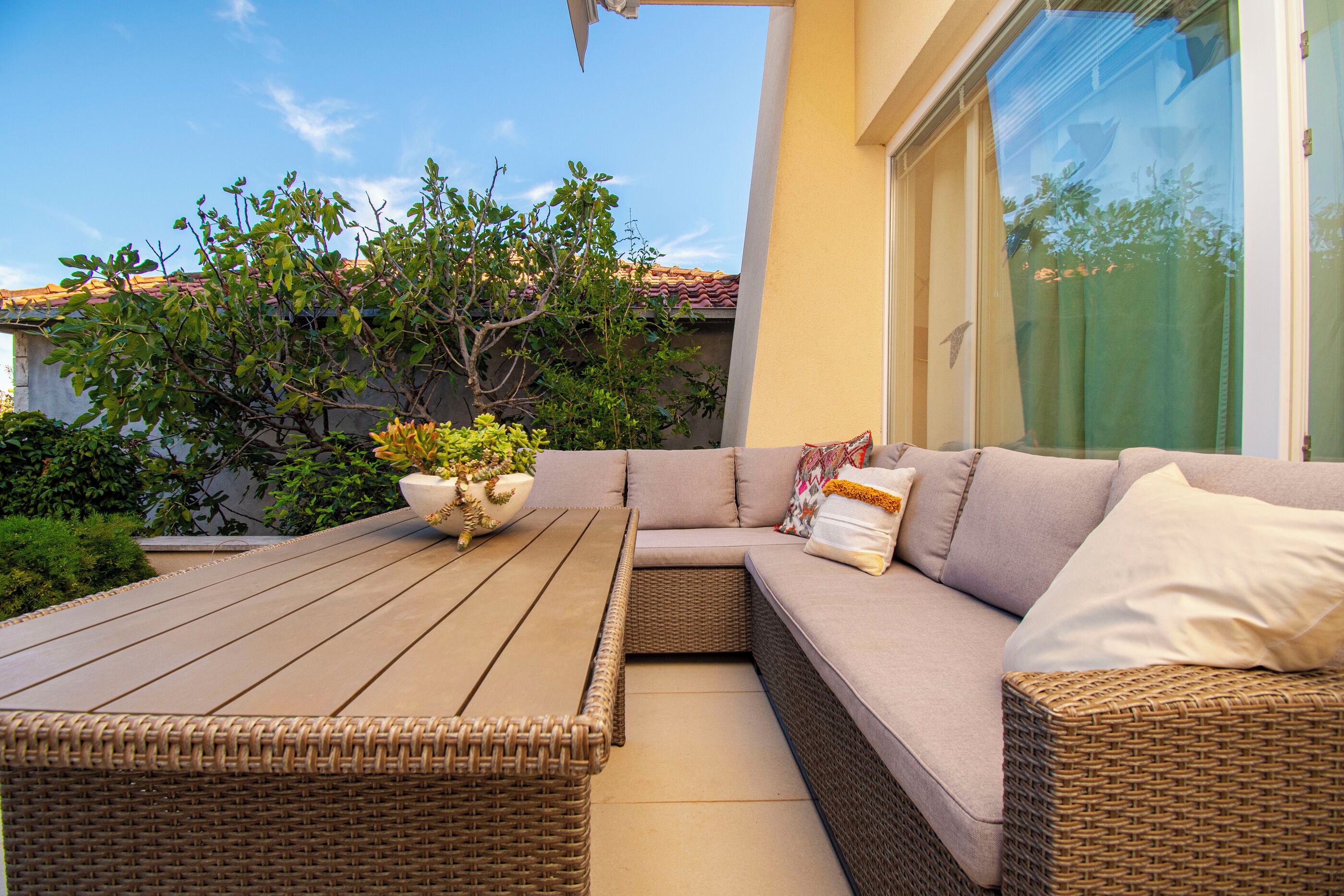 An outdoor seating area with a wooden table and a wicker sofa.