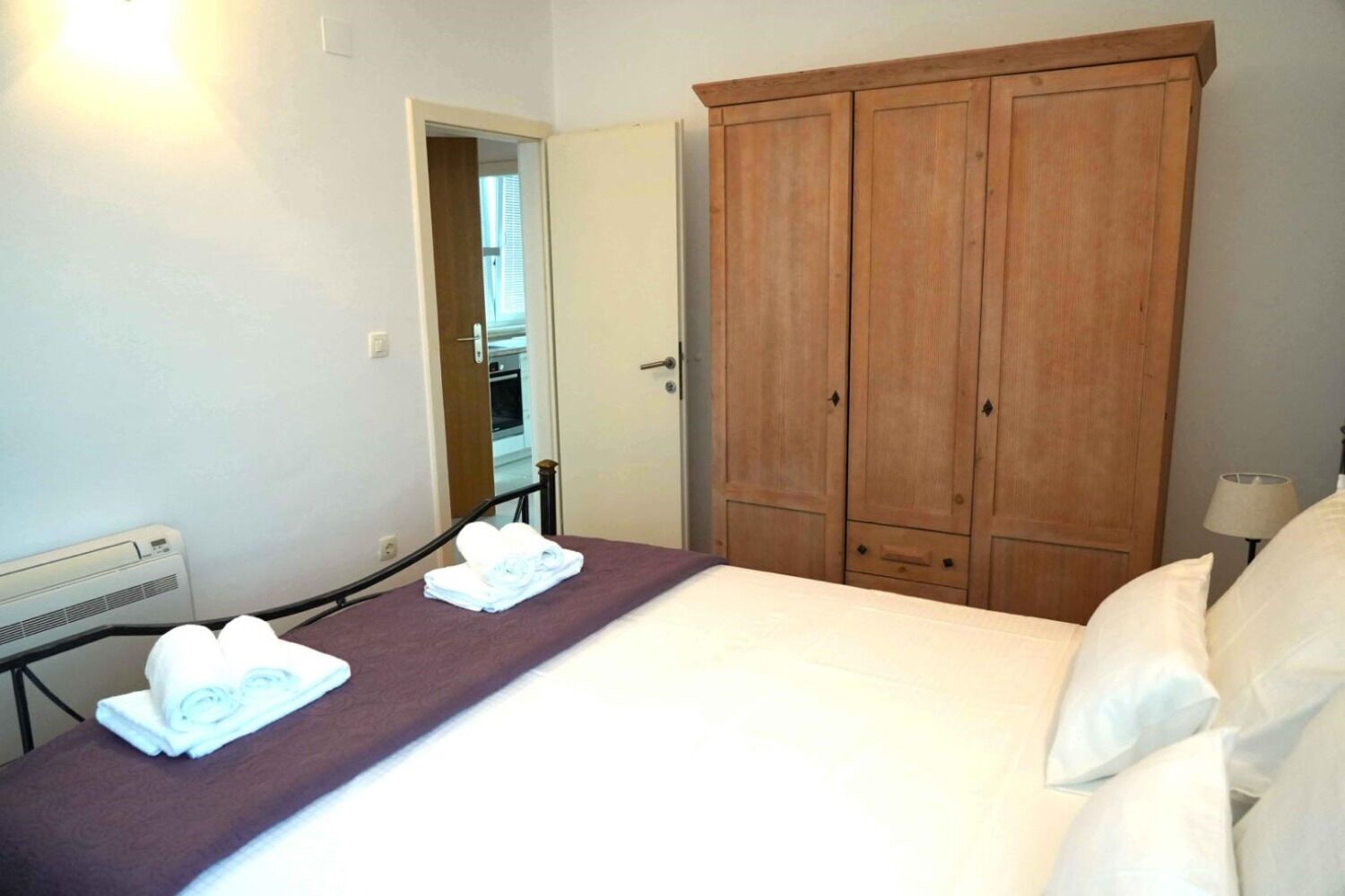 Une chambre d’hôtel avec un lit, une armoire en bois, un miroir et un radiateur.