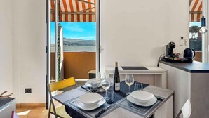 A dining area with a table set for two, a bottle of wine, and glasses. A view of the outdoors is visible through an open door. - La Scala Matta, Sea Lands (La Spezia)