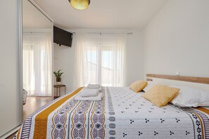 A bedroom with a bed, a TV mounted on the wall, and a potted plant. - Apartment Tomi (Trogir)