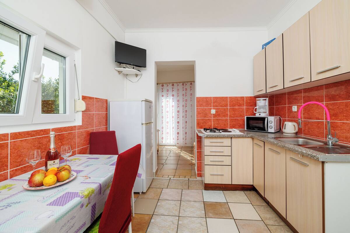 A compact kitchen with a dining table, a refrigerator, a microwave, and a sink.