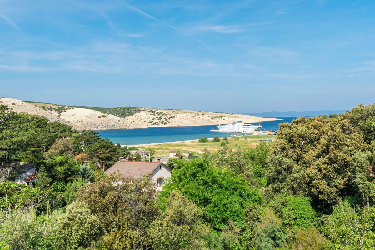 A coastal landscape with a white building, likely a hotel, overlooking a beach and the sea.