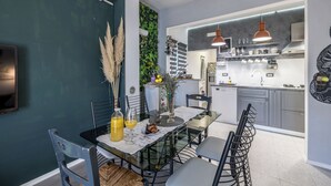 A modern kitchen with grey cabinets, a built-in oven, and a hanging light fixture. - Apartments Holiday Home Book (Opuzen)