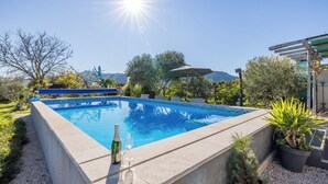 A swimming pool with a clear blue water, surrounded by potted plants and a pergola. - Apartments Holiday Home Book (Opuzen)