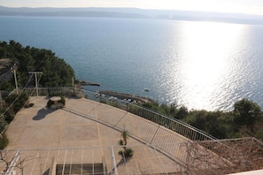 A coastal terrace with a view of the sea, a paved area, and a railing. - Apartments Paradiso (Omis)