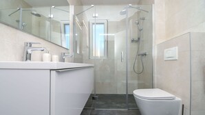Une salle de bain moderne avec une douche à parois de verre, un lavabo blanc et des toilettes.