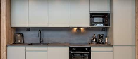 A compact kitchen with a built-in microwave, a coffee maker, and a dishwasher.
