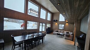 A spacious living area with a wooden dining table and chairs, a sofa, and a television. - Trysil Ski-in/out Apt, newly built (Trysil)