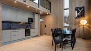A modern kitchen with a dining area, wooden walls, and a large window. - Trysil Ski-in/out Apt, newly built (Trysil)