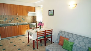 A compact kitchen with wooden cabinets, a tiled backsplash, and a dining table with chairs. - House Anamaria (Posedarje)