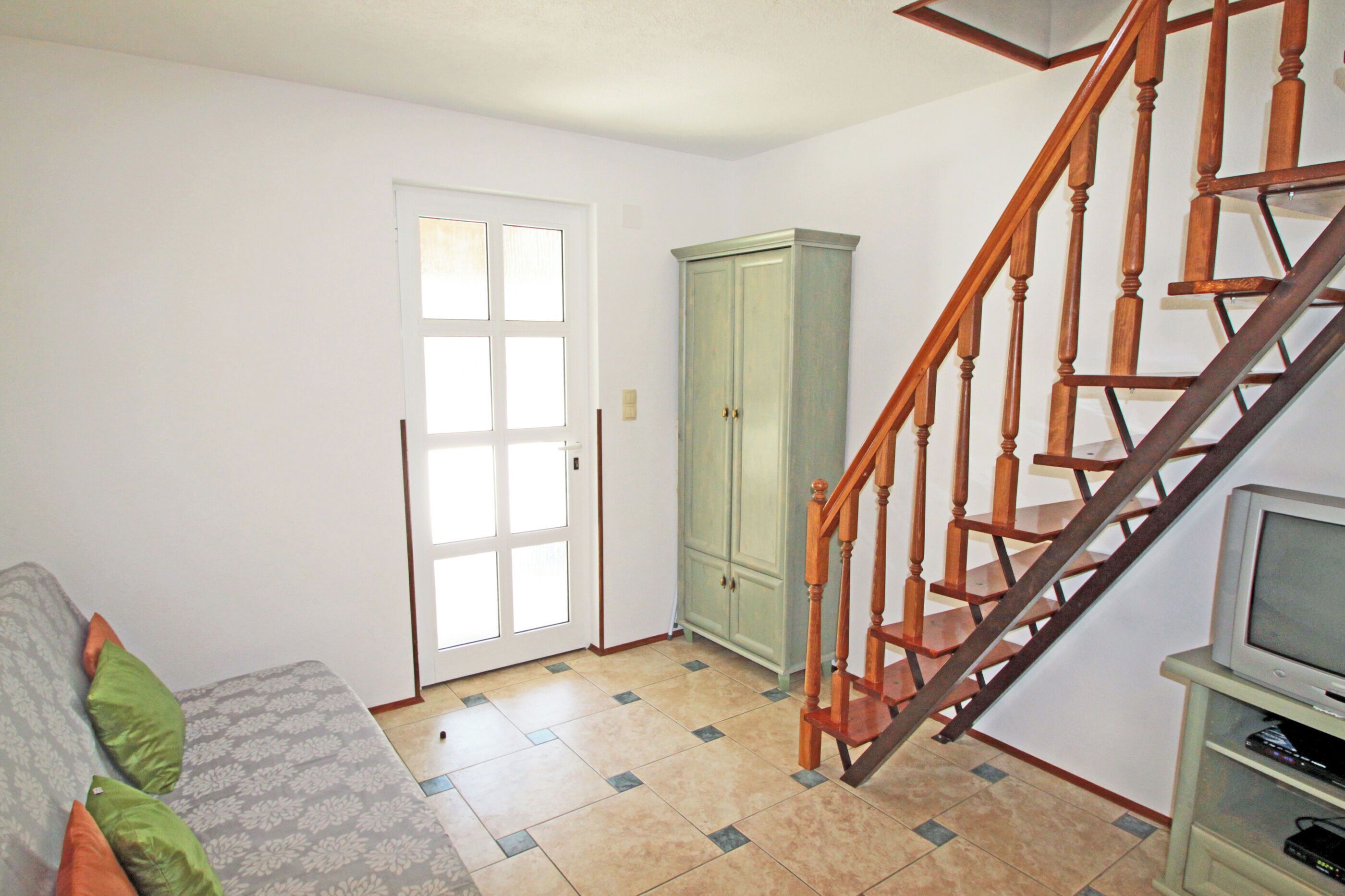 Un salon comprenant un canapé, un meuble, un escalier et un téléviseur.