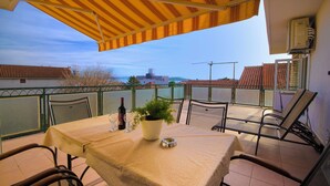 A covered outdoor dining area with a table, chairs, and a potted plant. - Apartment Goran Center (Vodice)