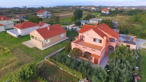 A residential area with houses featuring red-tiled roofs and a central building with a balcony. - Apartments Lea Patrik Mara (Nin)