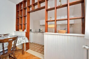 Una cucina con mobili bianchi, un tavolo da pranzo in legno con sedie e una finestra con cornice in legno.