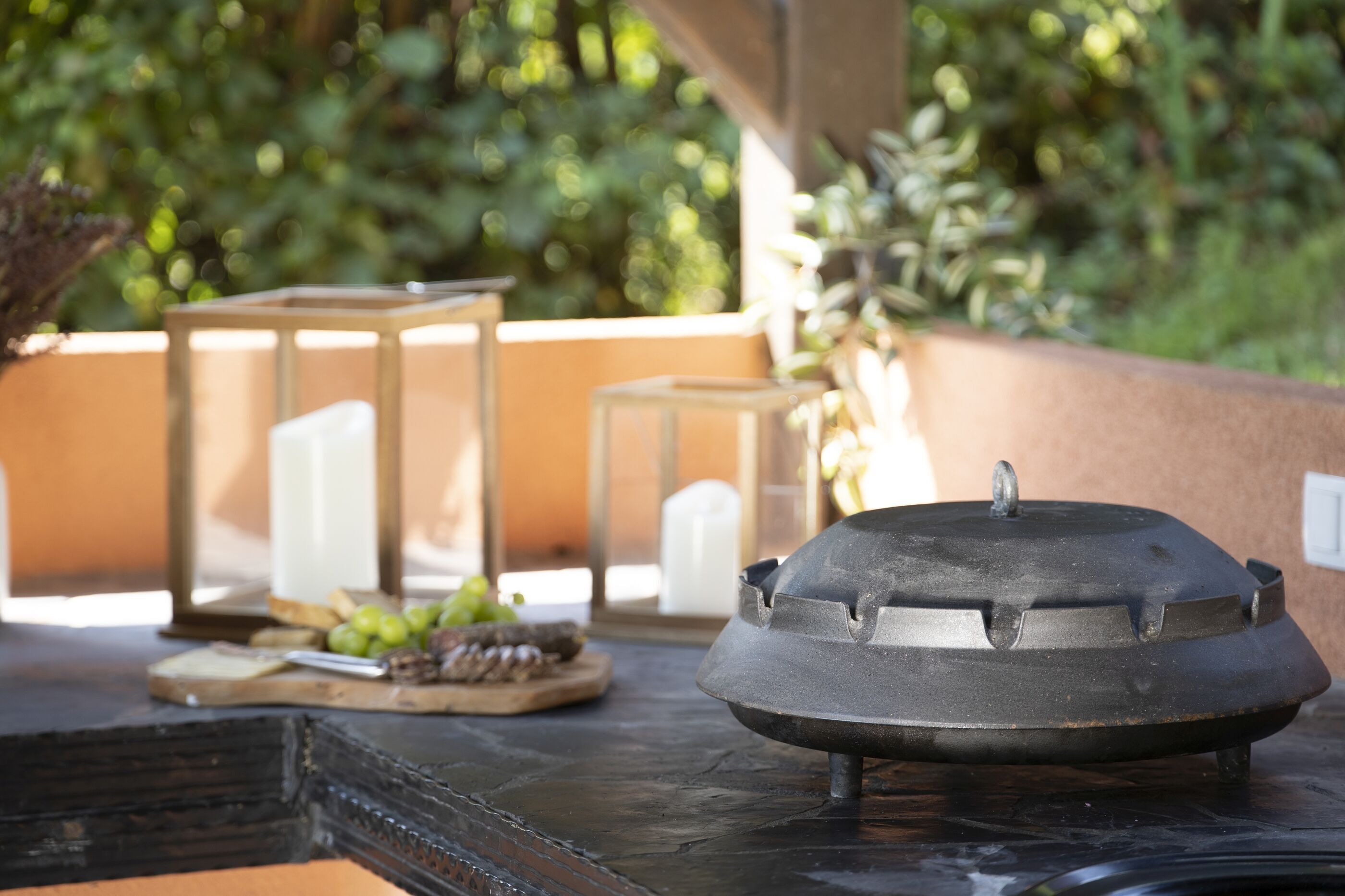 Une table sur laquelle se trouve un objet noir, peut-être un pot, ainsi qu’une planche en bois avec des raisins et un couteau.