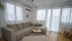 A modern living room with a beige sectional sofa, a round coffee table, and a wooden floor. - House Casa Huerta (Netretic)