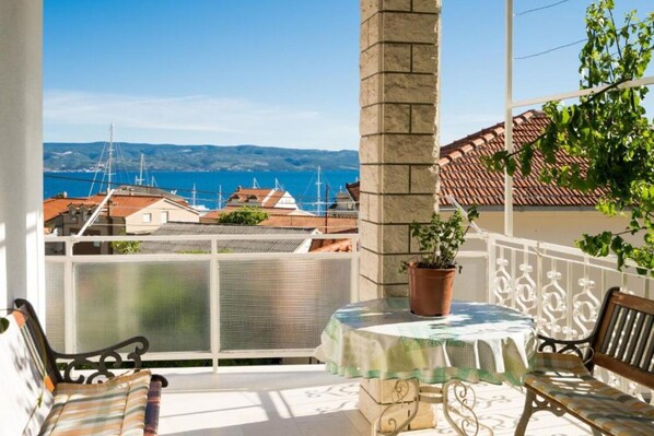 A balcony with a table, chairs, and a potted plant. - Apartment Zeljka (Dugi Rat)