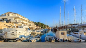 Un puerto deportivo con varias embarcaciones amarradas, un edificio con balcones y un cielo azul despejado.