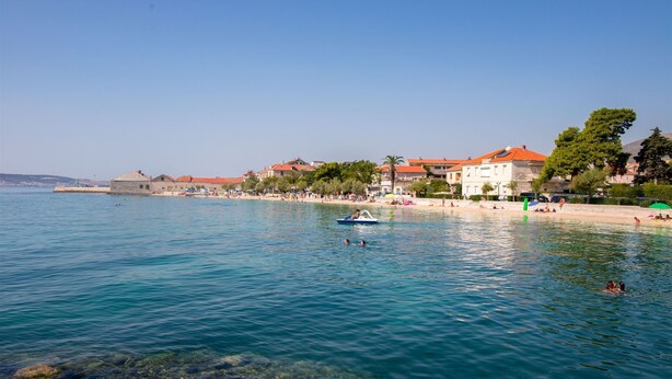 A coastal town with clear waters, a beach, and buildings with red roofs. - House Sun (Kastela)