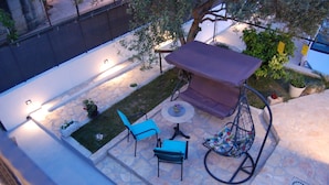 A patio area with a stone floor, a swing chair, and a table with a canopy. - House Sun (Kastela)