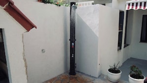 A corner of a building with a stone floor, a black vertical object, and two potted plants. - House Sun (Kastela)