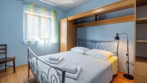 A bedroom with a bed, a chair, a wardrobe, and a floor lamp. - Apartment Nikica (Supetar)