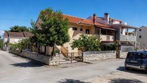 A two-story house with a stone wall and a red-tiled roof. - Apartment Nikica (Supetar)