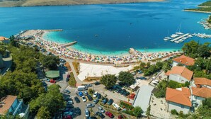 An aerial view of a coastal area with a beach, marina, and surrounding buildings. - Apartments Miro (Crikvenica)