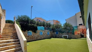 A courtyard with artificial grass, stone walls, and a staircase leading up to a building. - Apartments Aura (Seget)