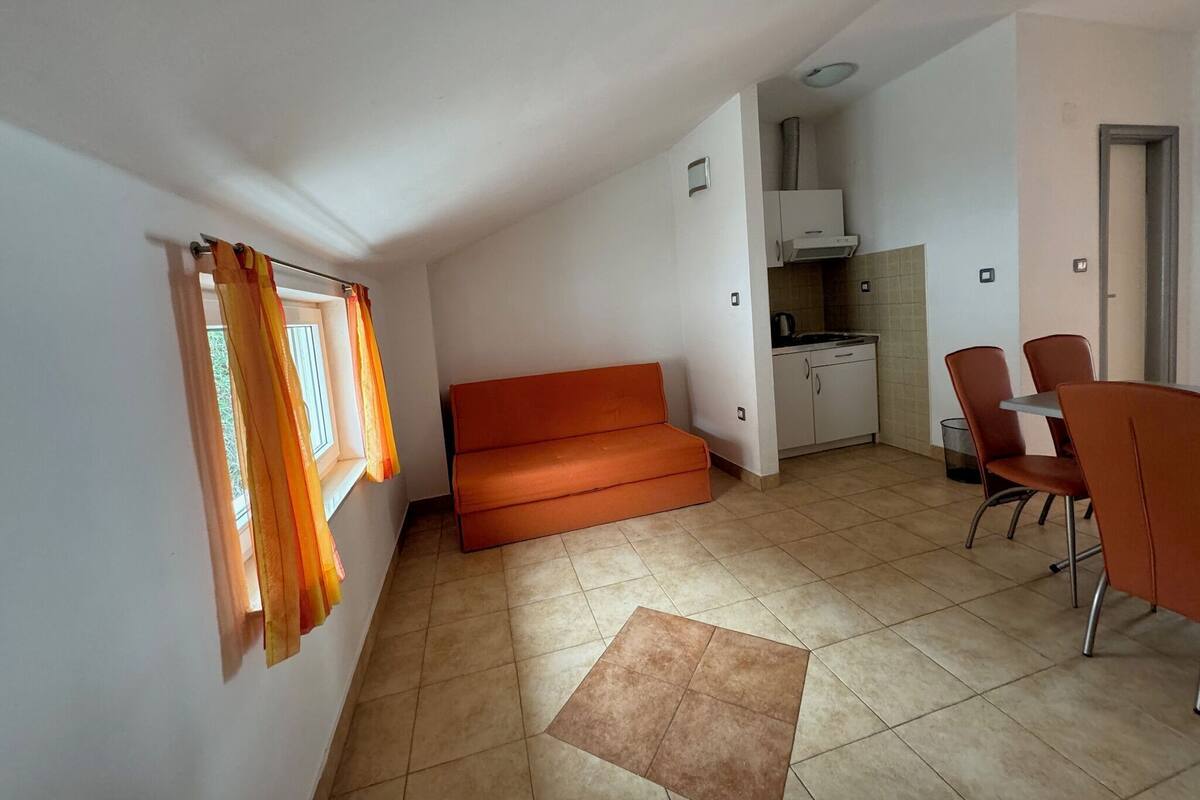 Un espacio habitable compacto con kitchenette, sofá y comedor.
