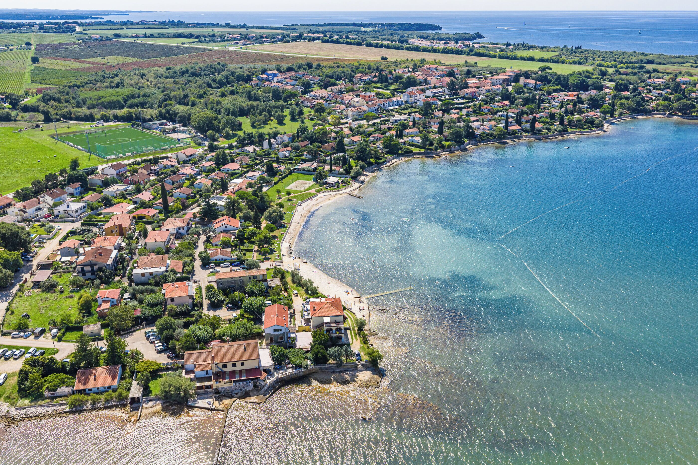A coastal town with residential buildings, a beach, and a clear view of the sea.