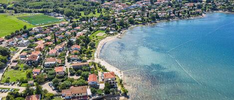 A coastal town with residential buildings, a beach, and a clear view of the sea.