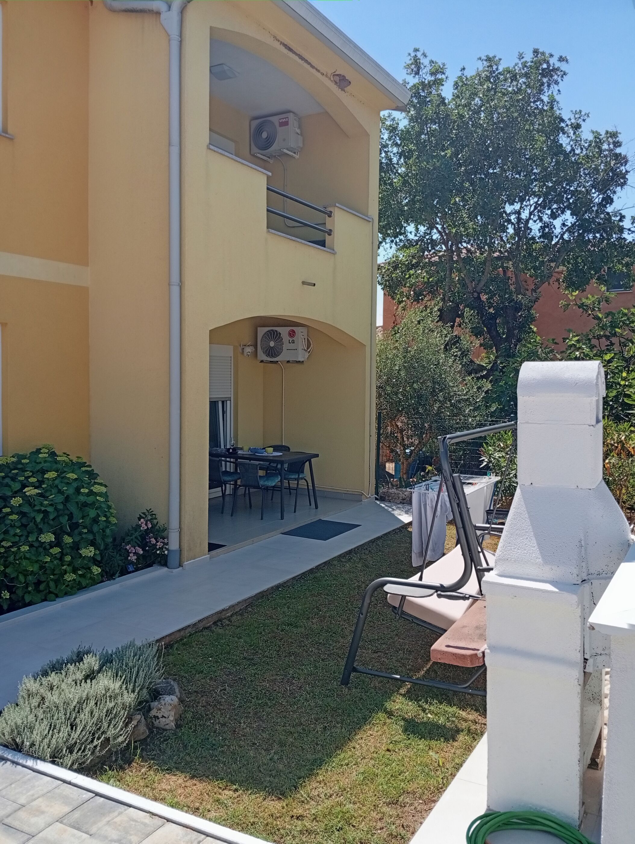 Un bâtiment à deux étages doté d’un espace extérieur aménagé pour s’asseoir et d’une terrasse couverte.