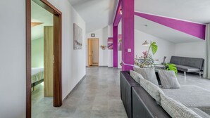 A modern living room with a sofa, a dining table with chairs, and a staircase leading to another level. - Apartments Deepwater (Split)