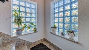 A room with two windows, each with a grid pattern and potted plants on the ledges. - Apartments Deepwater (Split)